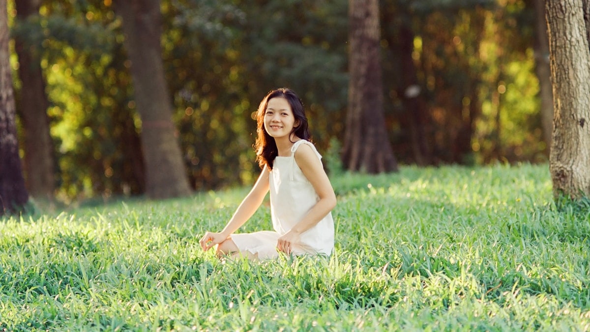 A woman in a white dress is sitting in the grass